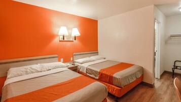 A hotel room with two beds, a nightstand, and a wall-mounted lamp.