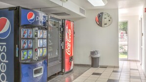 A vending area with Pepsi and Coca-Cola machines, a trash bin, and a wall clock. - Motel 6 Mojave, CA (Mojave)