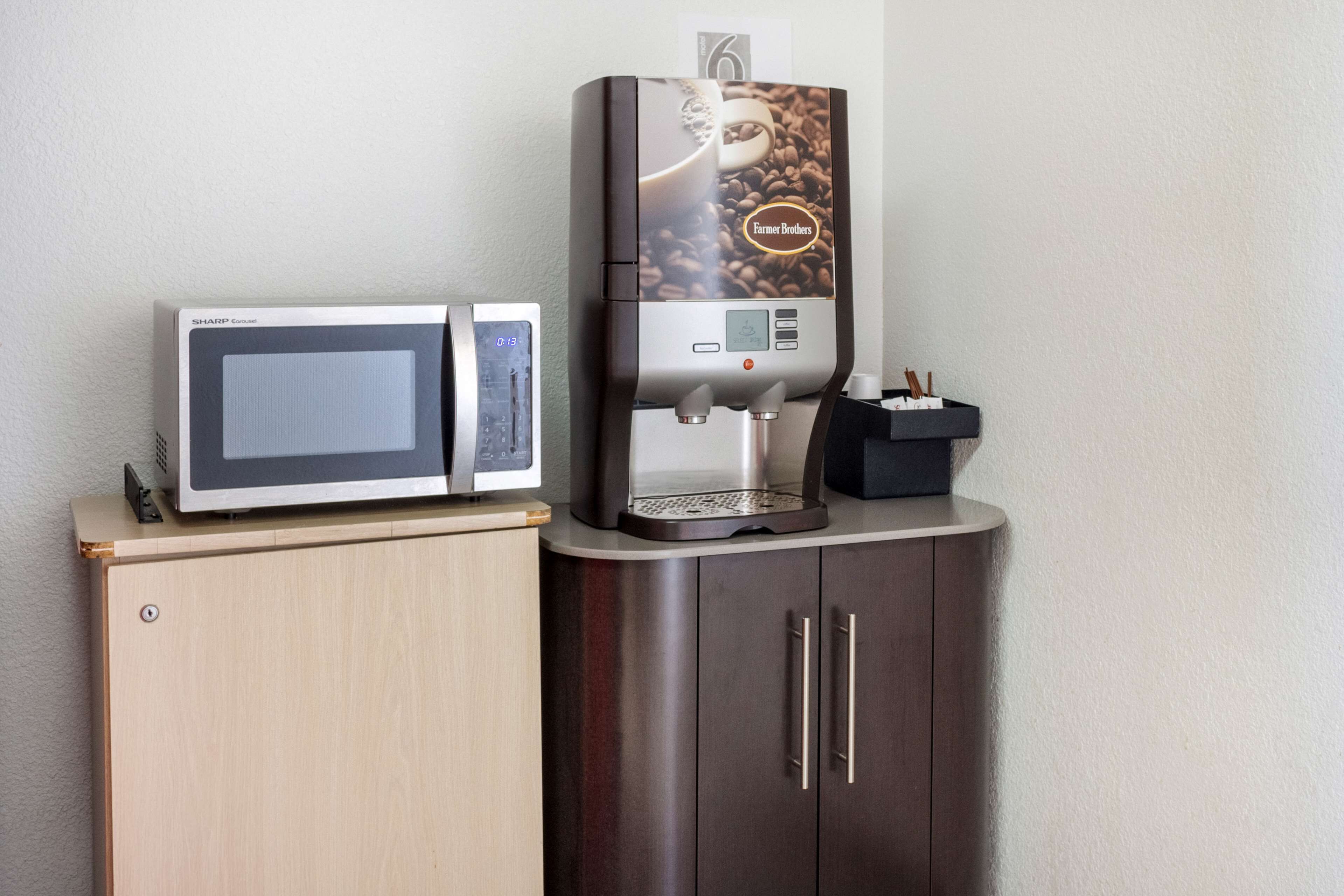 A microwave and a coffee machine on a wooden cabinet.
