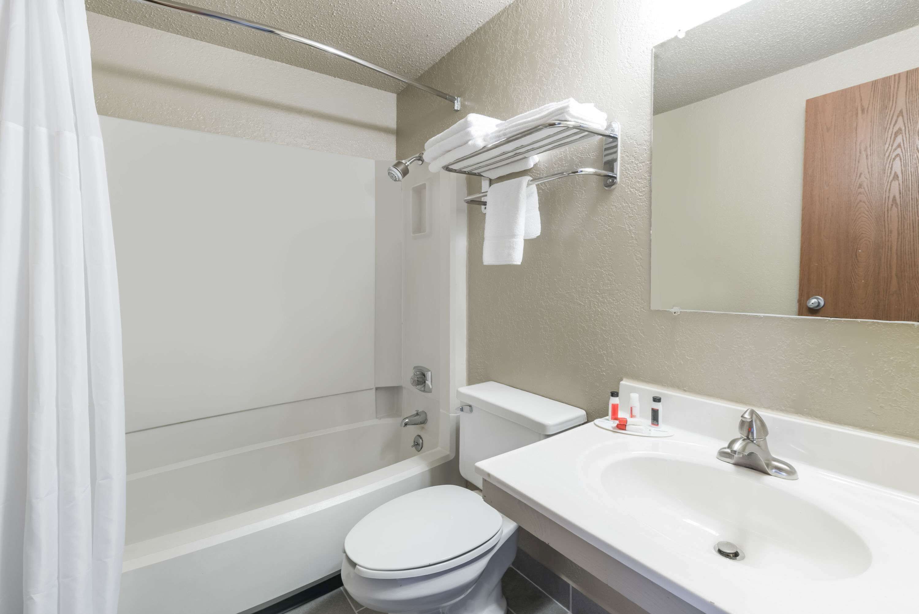 Un baño con bañera, inodoro, lavamanos y un perchero para toallas.