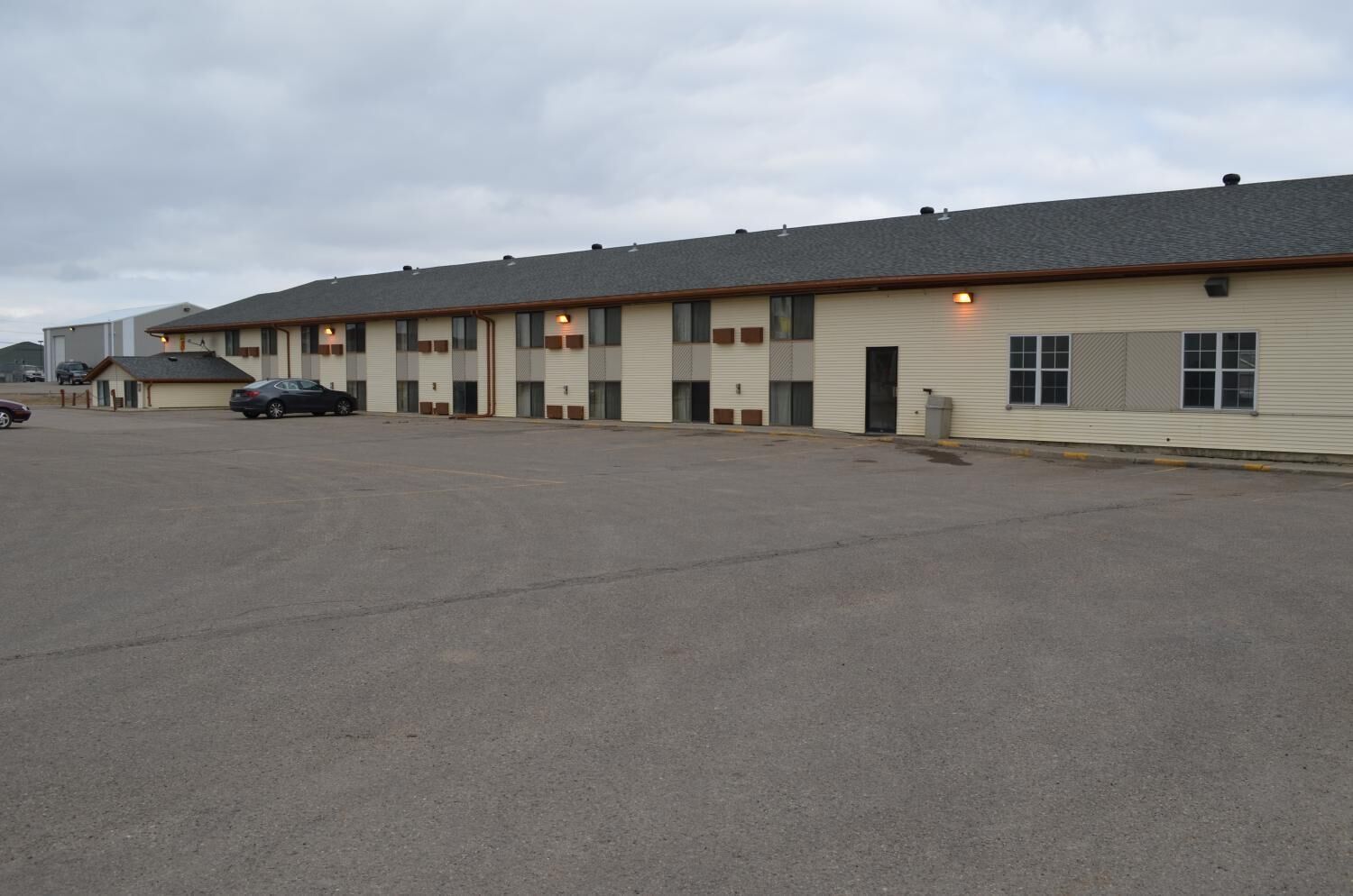 A row of single-story motel buildings with a parking lot in front.