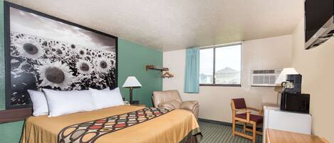 A hotel room with a large bed, a desk, a chair, a TV, and a window with curtains.