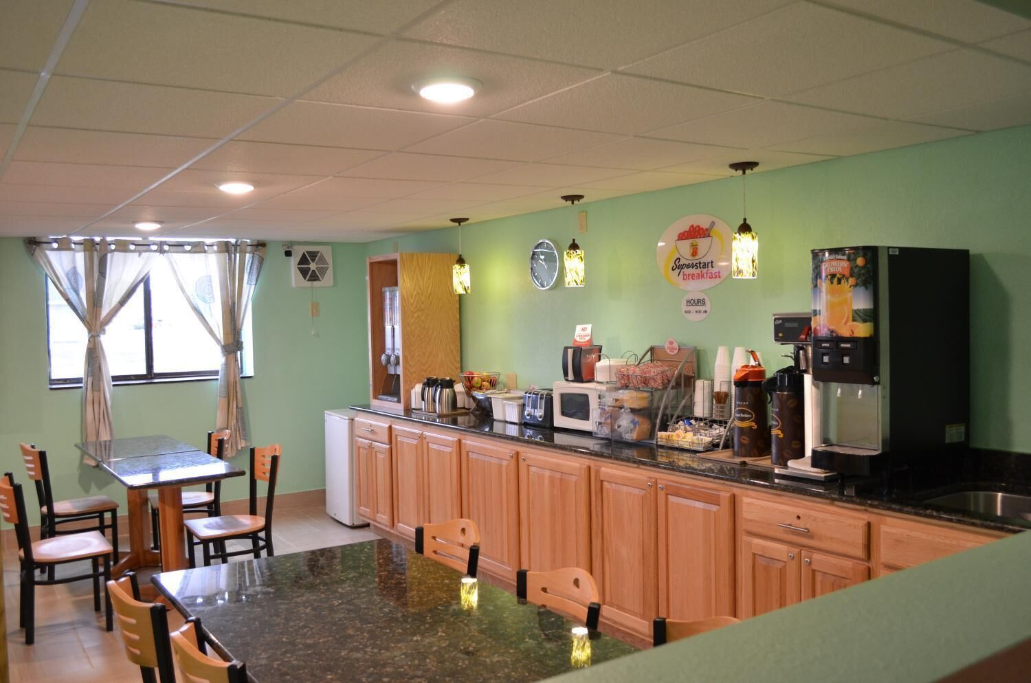 A kitchen with wooden cabinets, a granite countertop, a microwave, a coffee machine, and a refrigerator.