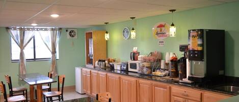 A kitchen with wooden cabinets, a granite countertop, a microwave, a coffee machine, and a refrigerator.