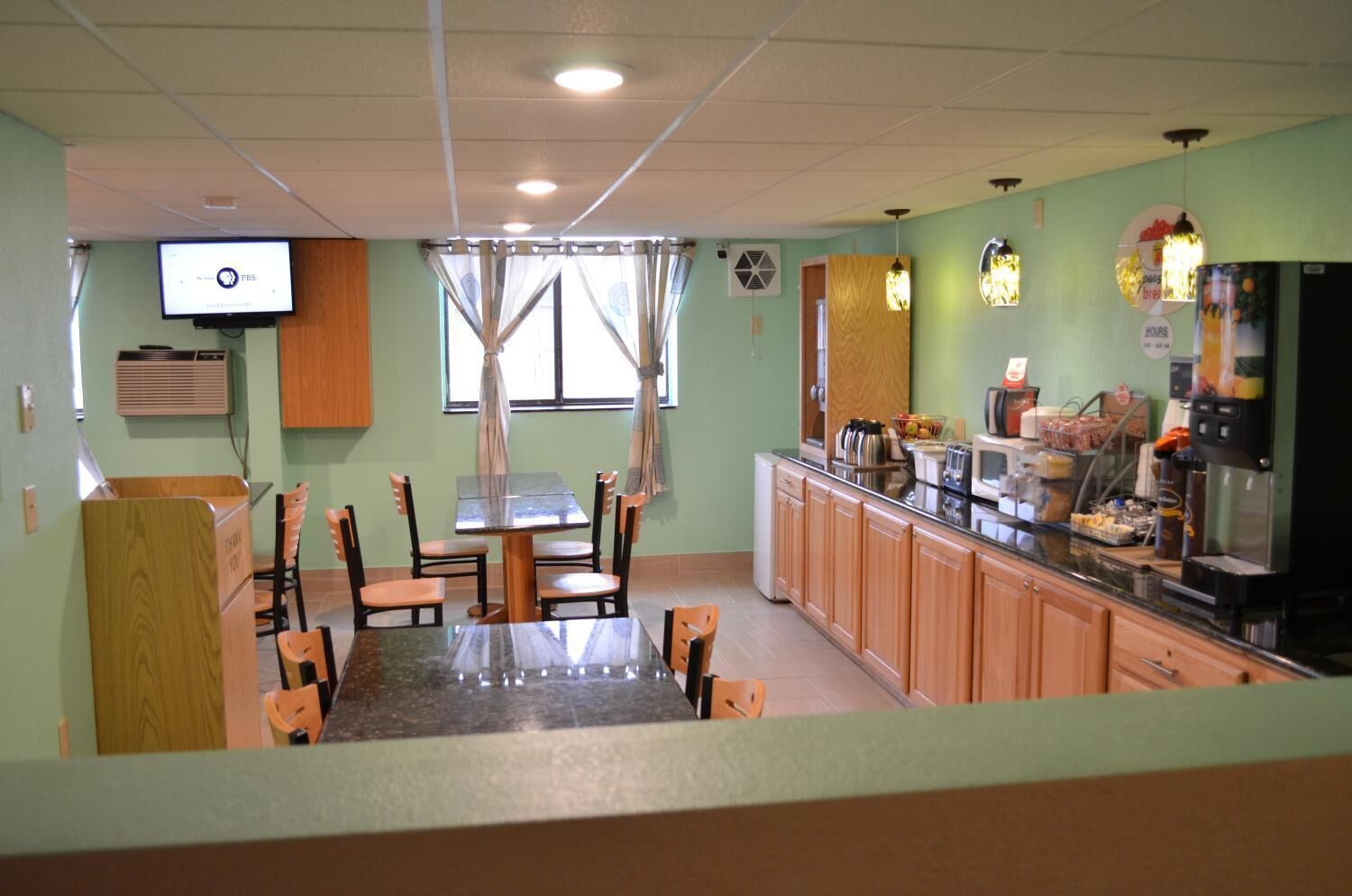 A restaurant with a dining area, kitchen, and a TV displaying PBS.