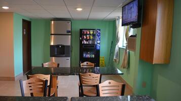 A small kitchenette with a refrigerator, microwave, and coffee machine. There are wooden chairs around a granite countertop.
