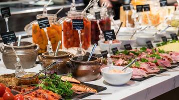 Un bufé con diversos alimentos, incluyendo carnes, quesos y salsas.