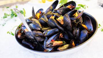 A bowl of mussels with a spoon.