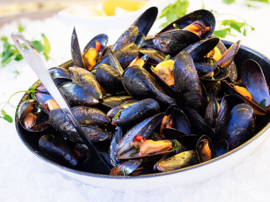 A bowl of mussels with a spoon.