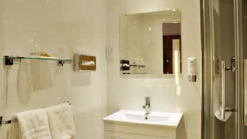 Een moderne badkamer met een douchecabine van glas, een witte wastafel en een handdoekrek.