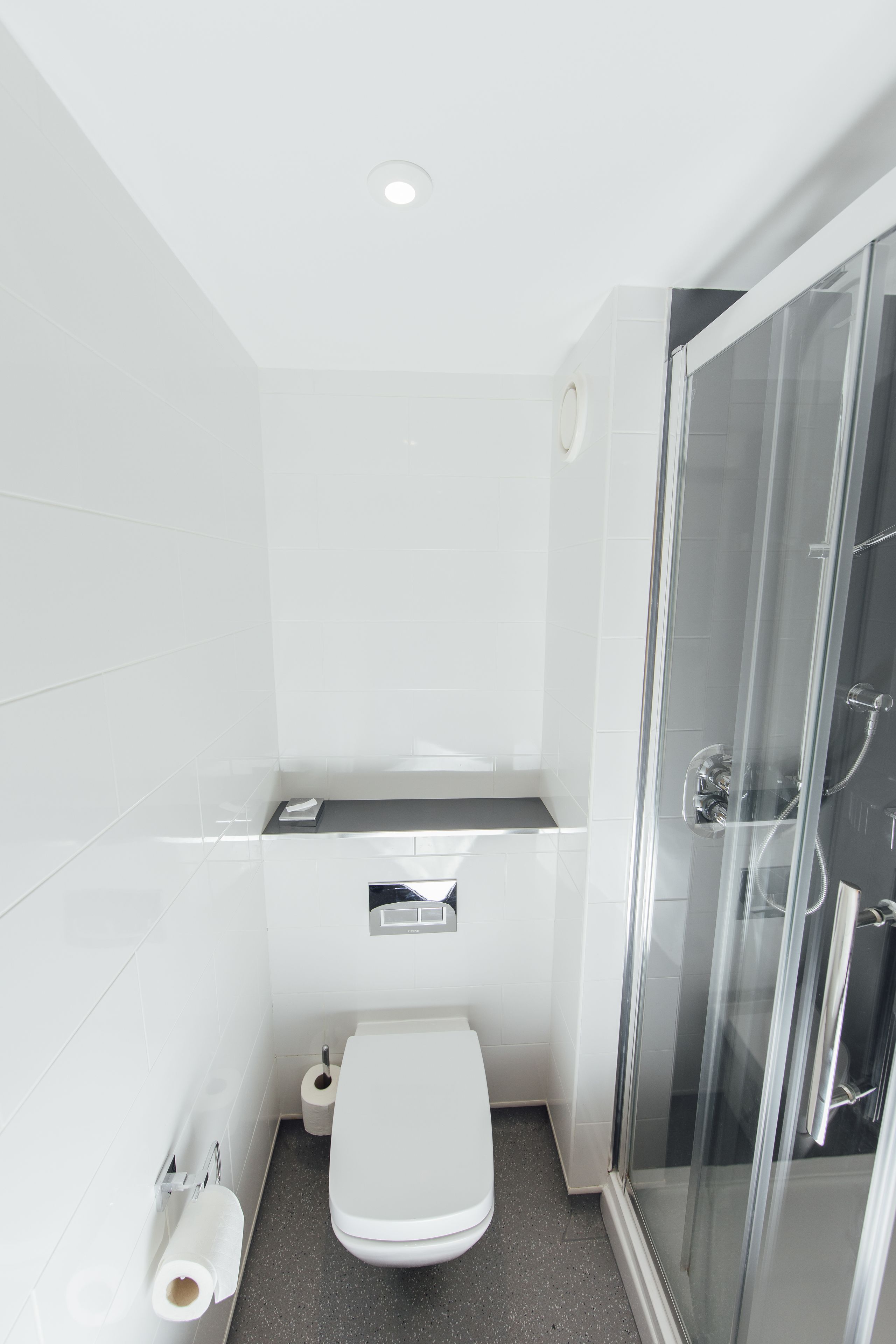 A modern bathroom with a toilet, sink, and glass shower enclosure.