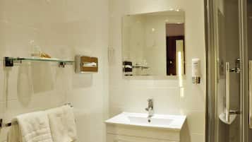 A modern bathroom with a white sink, a glass shower enclosure, and a mirror above the sink.