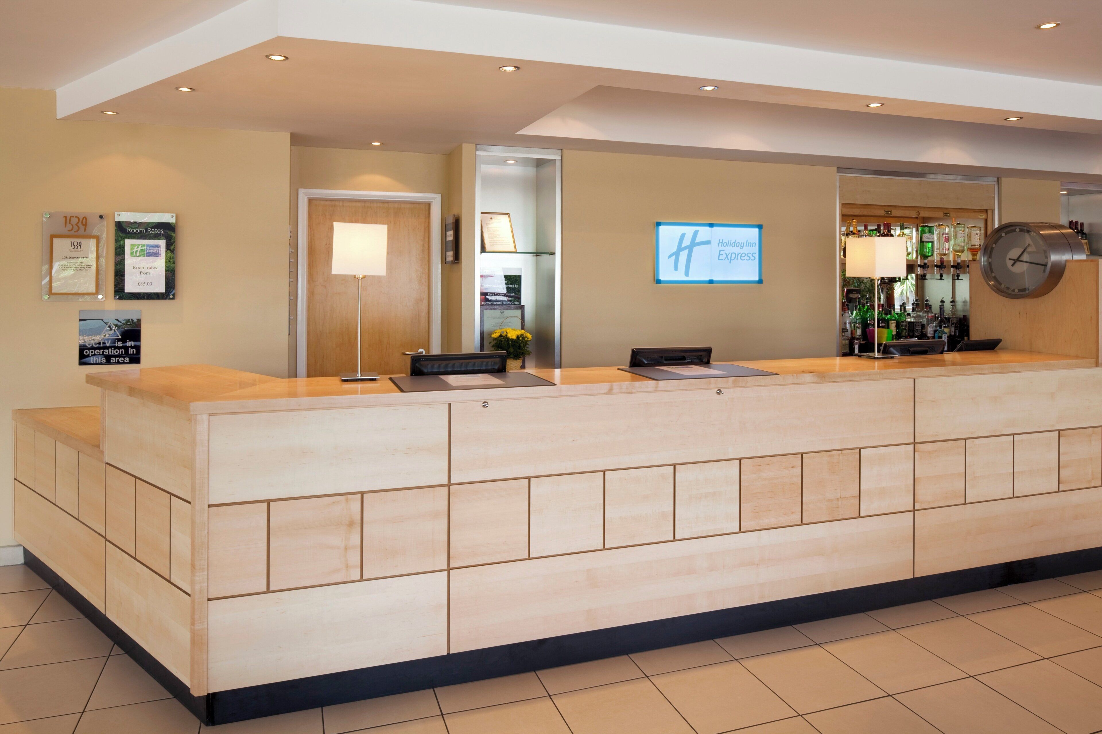 Et hotellets receptionområde med reception, et ur og et Holiday Inn Express skilt.