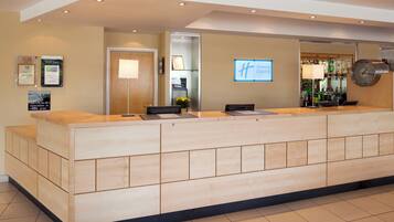 A hotel reception area with a reception desk, a clock, and a Holiday Inn Express sign.