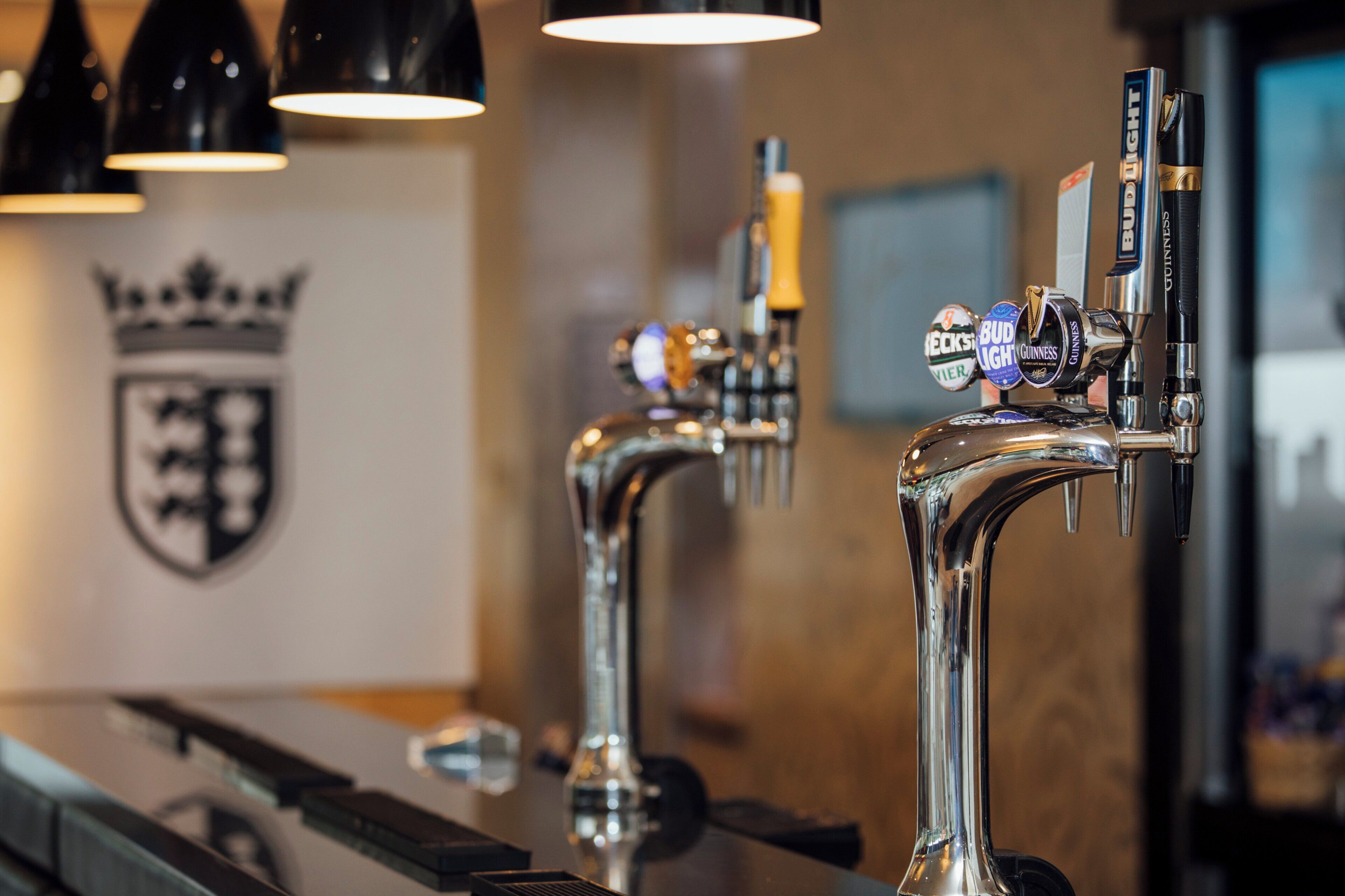 A bar with multiple taps, including Guinness and Bud Light, and a shield emblem on the wall.