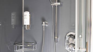 A modern shower with a handheld showerhead and a wall-mounted faucet.