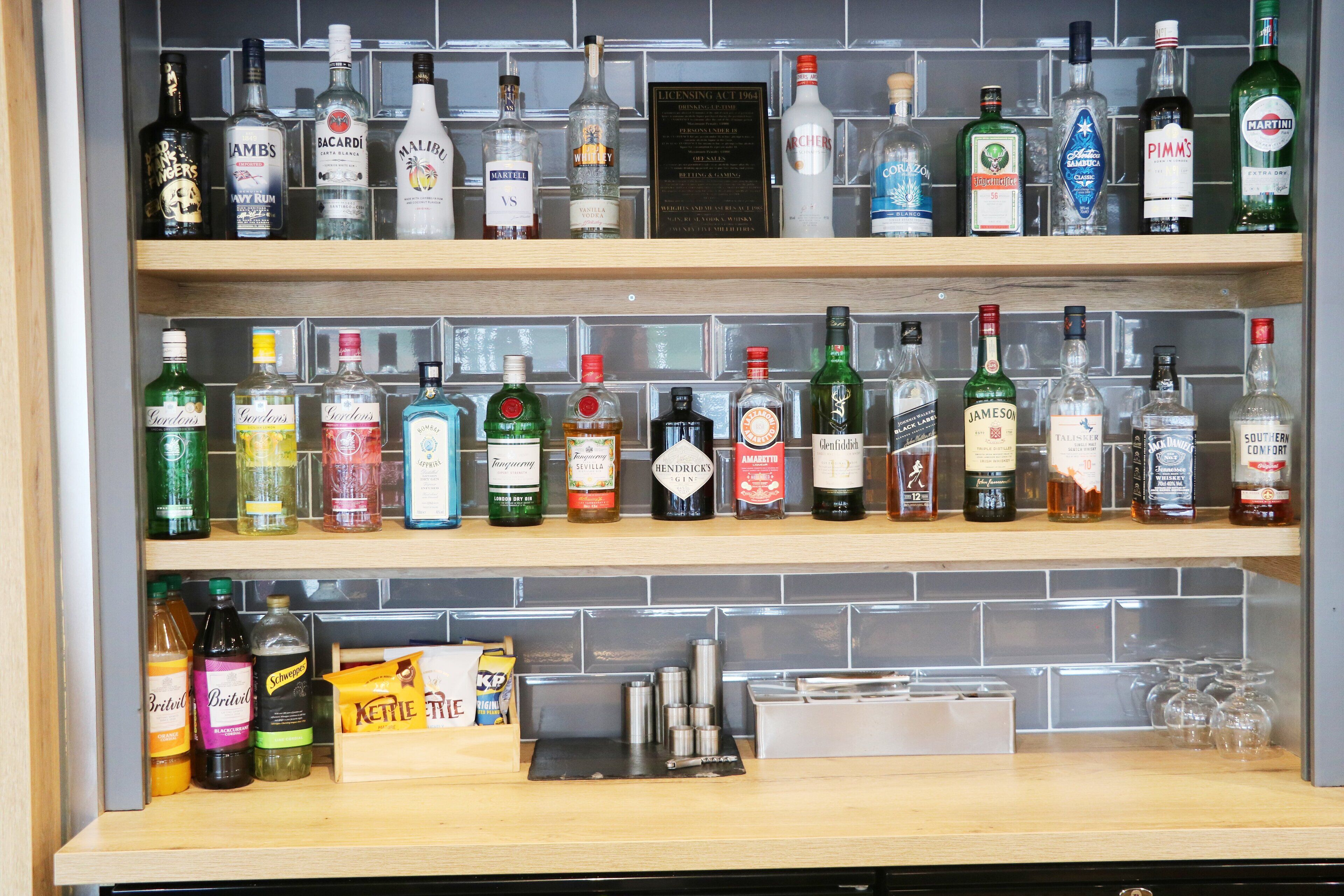 Zona de bar con varias estanterías llenas de botellas de licores.