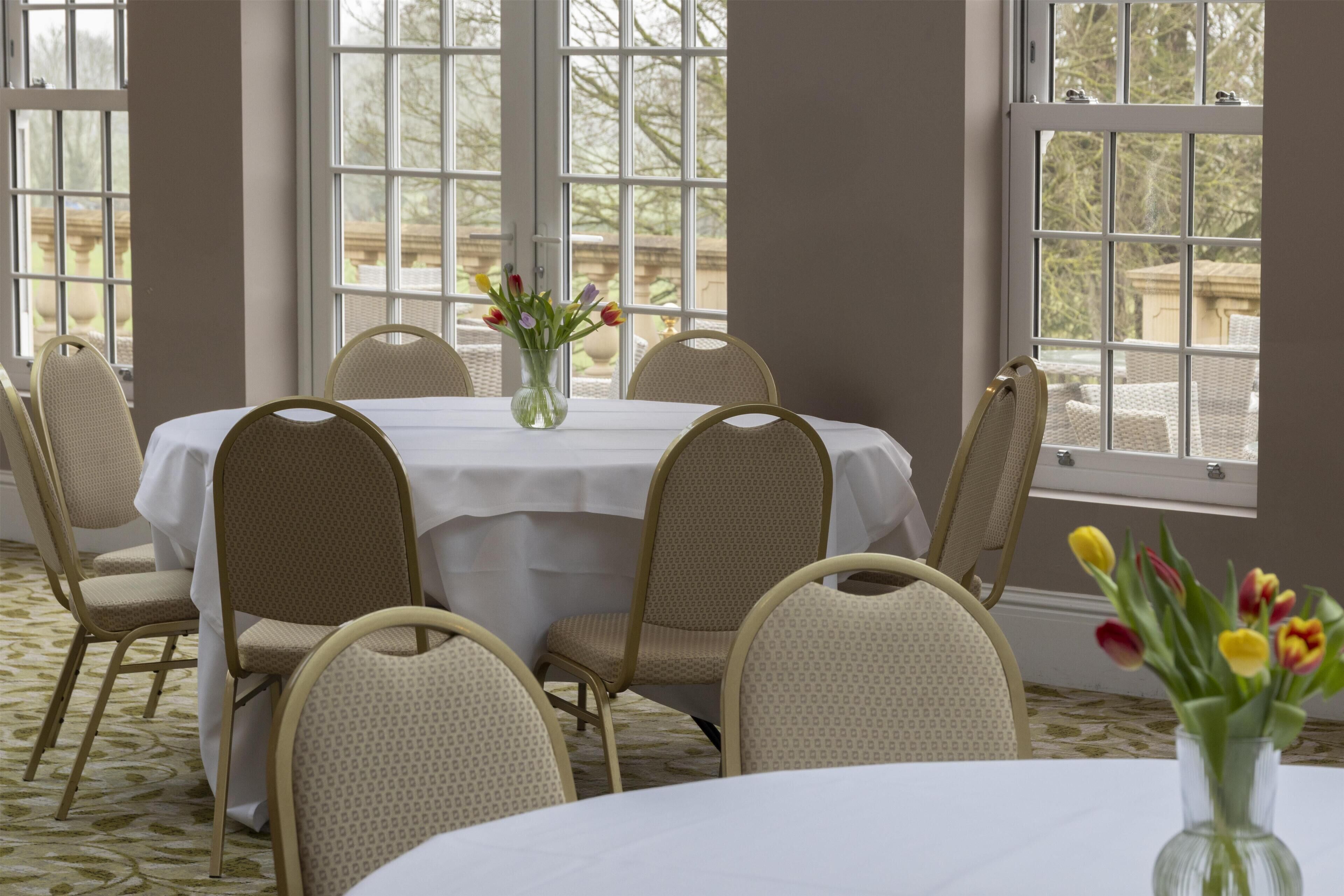 Un comedor con una mesa redonda, seis sillas y un florero.