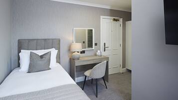 Een hotelkamer met een bed, een bureau, een stoel, een spiegel en een deur.