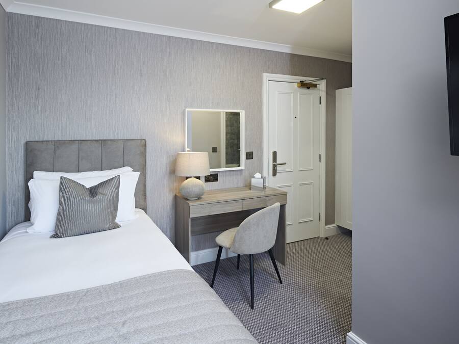 Een hotelkamer met een bed, een bureau, een stoel, een spiegel en een deur.