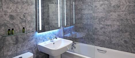 A modern bathroom with a toilet, sink, and bathtub.