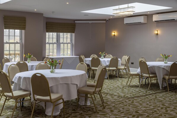 A conference room with round tables, beige chairs, and white tablecloths. - The Riverside, WorldHotels Distinctive (Salisbury)