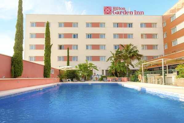 Une zone avec piscine, avec un hôtel Hilton Garden Inn en arrière-plan.