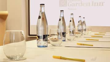 Una mesa con vasos y botellas vacías, un bolígrafo amarillo y una pantalla mostrando el logotipo de Hilton Garden Inn.