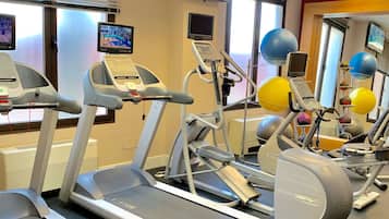 Un gimnasio con cintas de correr, elípticas y pelotas de ejercicio.