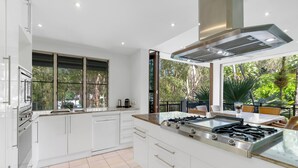 Cocina moderna con armarios blancos, una isla grande con estufa a gas y vistas al exterior.