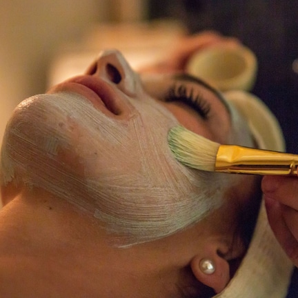 A person receiving a facial treatment with a brush.