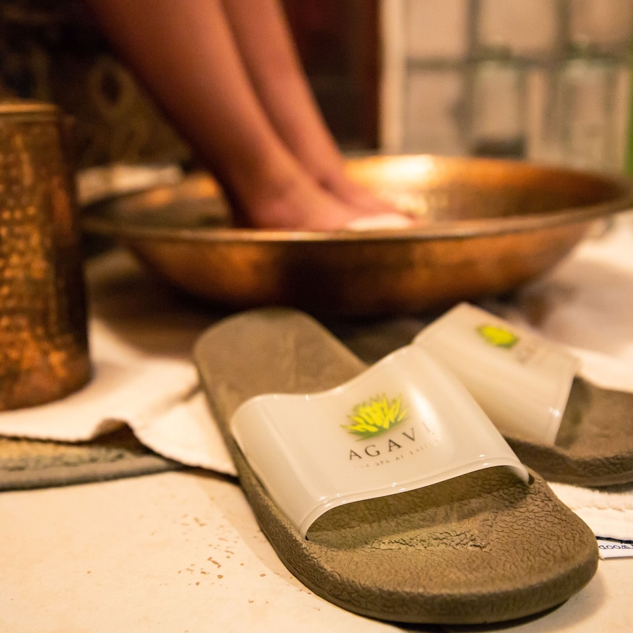 A pair of slippers with a logo, a metal container, and a bowl on a table.