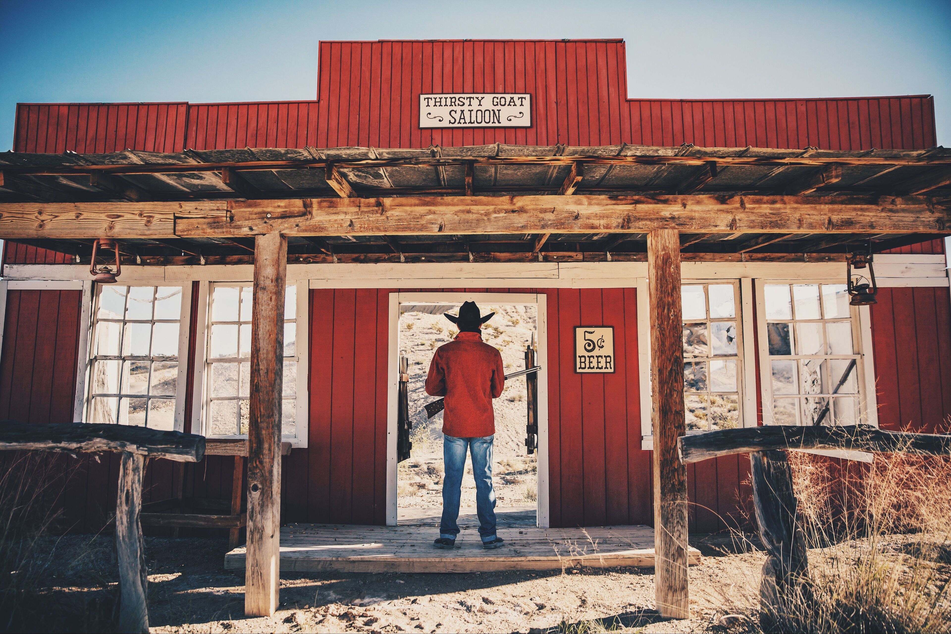A rustic saloon with a wooden facade and a sign reading "Thirsty Goat Saloon."