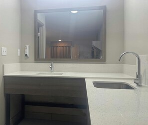A bathroom with a large mirror, a sink, a faucet, and a towel rack. - Red Roof Inn Orangeburg (Orangeburg)