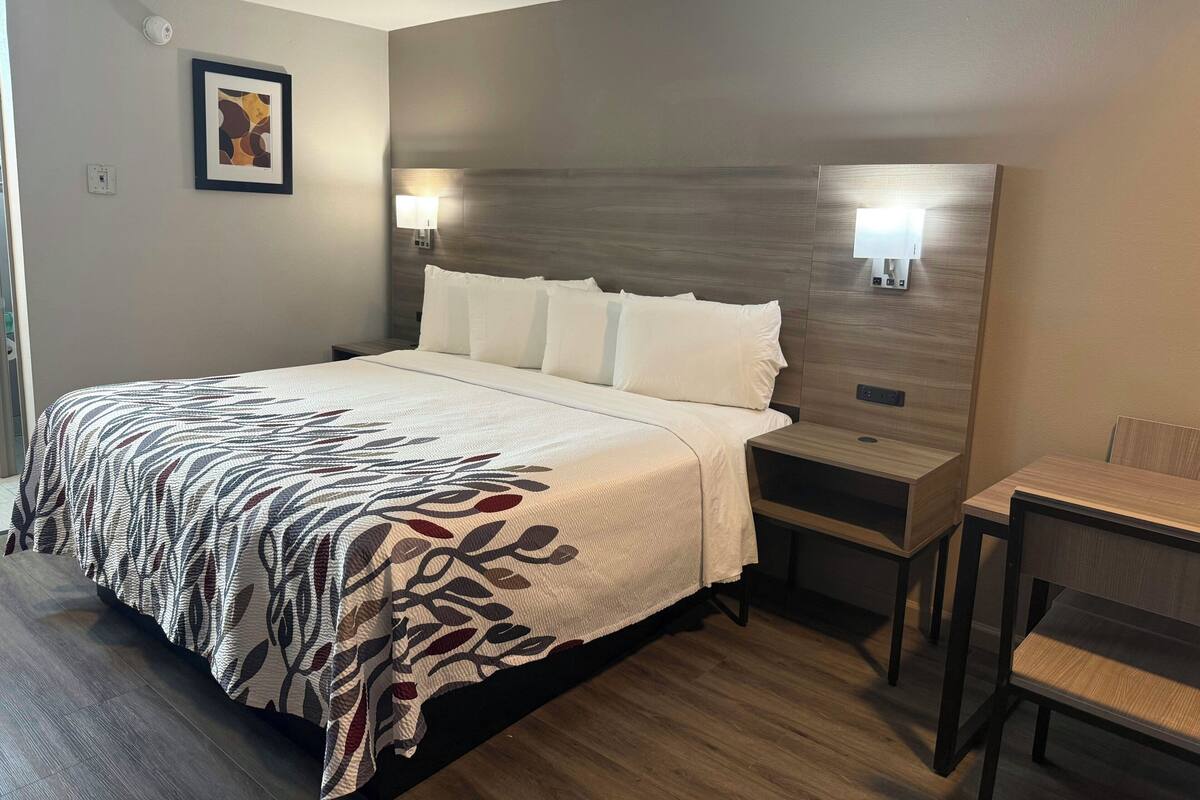 A hotel room with a large bed, bedside tables, a desk, and a chair.