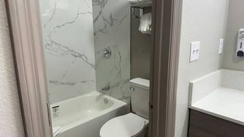 A bathroom with a bathtub, toilet, and a shower area.