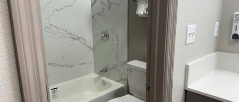 A bathroom with a bathtub, toilet, and a shower area.