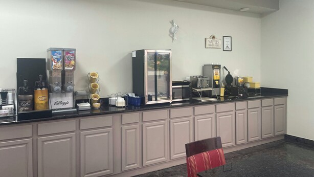 A hotel reception area with a counter, coffee machines, and a refrigerator.