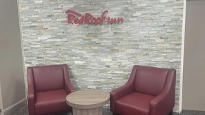 A Red Roof Inn with two red leather armchairs and a small wooden table in front of a stone-patterned wall.