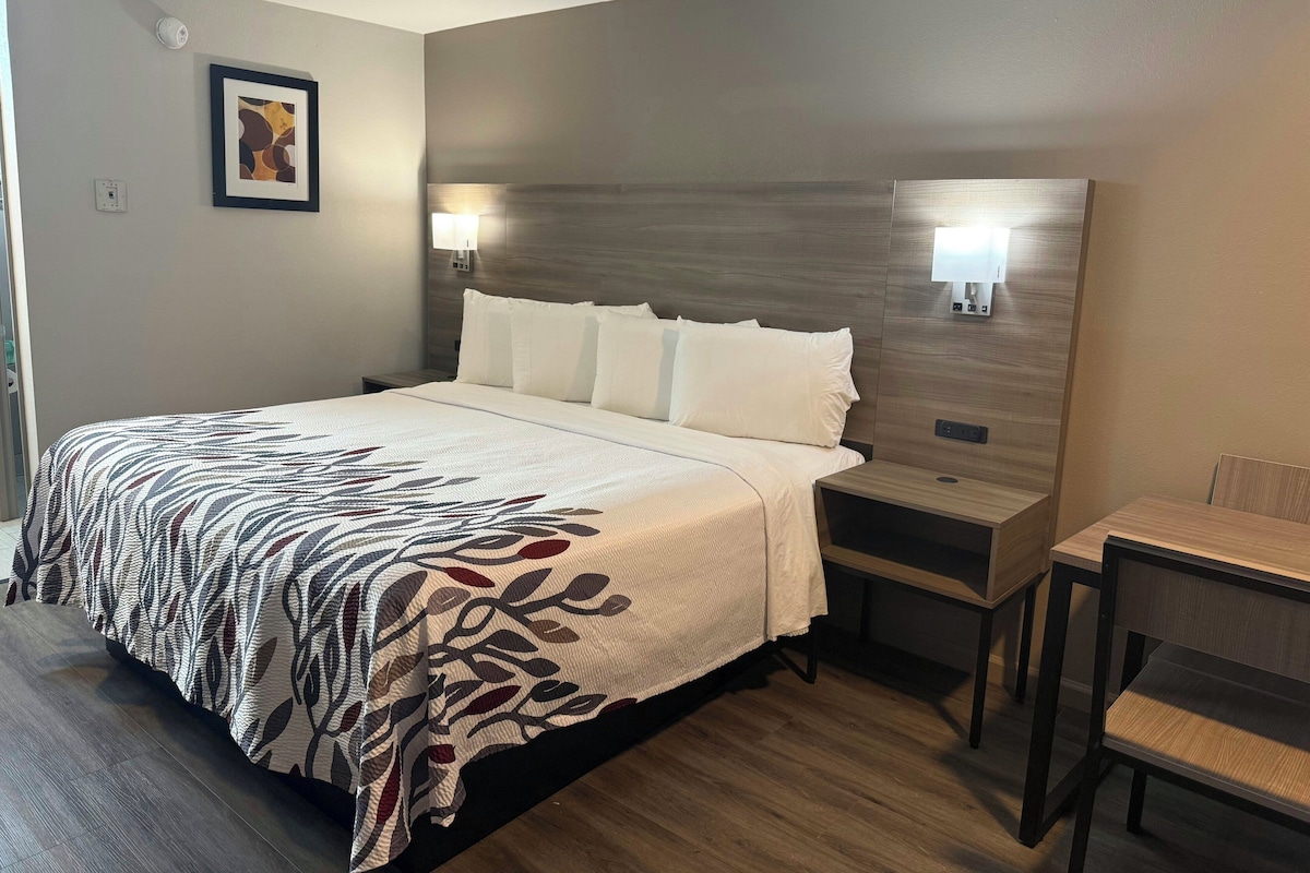Une chambre d’hôtel avec un grand lit, des tables de chevet, un bureau et une chaise.