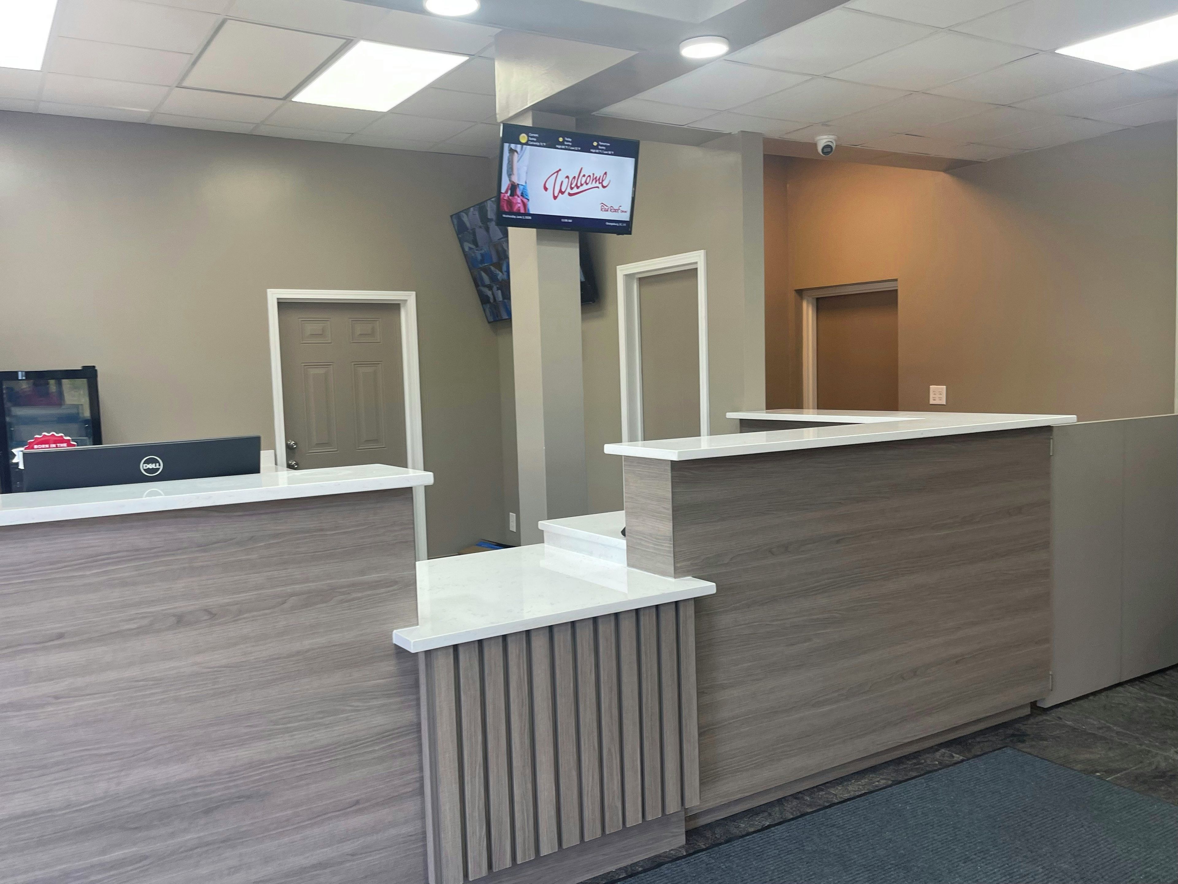 A reception desk with a flat-screen TV, a Dell computer, and a door.