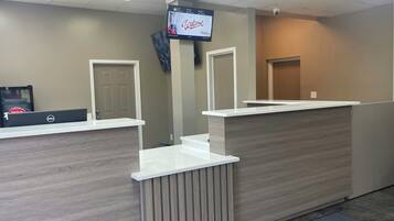 A reception desk with a flat-screen TV, a Dell computer, and a door.