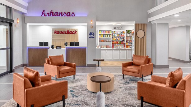 A lobby with orange leather sofas, a reception desk, a snack bar, and a patterned carpet. - DoubleTree by Hilton Springdale (Springdale)