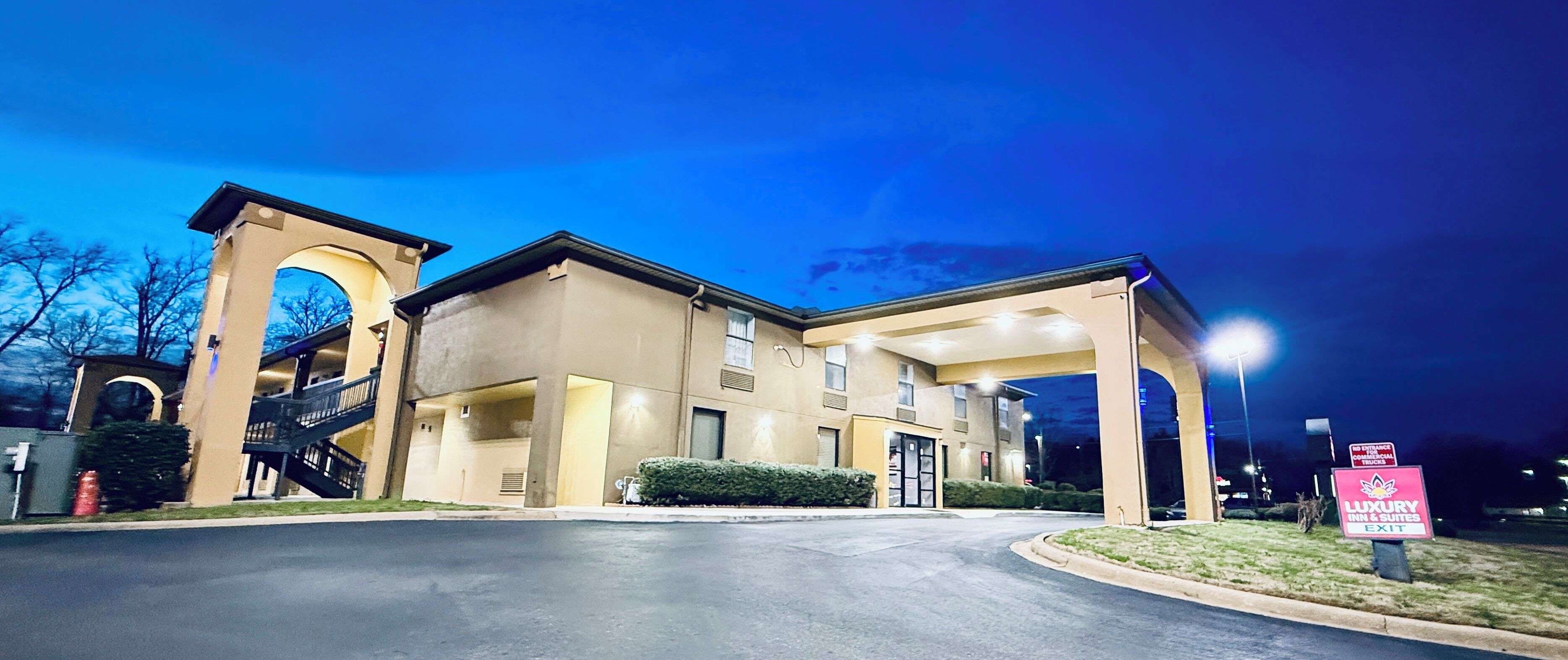 A hotel entrance with a covered walkway, a staircase, and a sign indicating a luxury inn & suites exit.