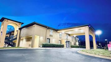 A hotel entrance with a covered walkway, a staircase, and a sign indicating a luxury inn & suites exit.