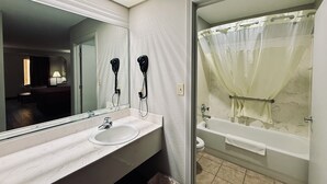 Un bagno con lavandino, specchio, asciugacapelli e vasca da bagno.