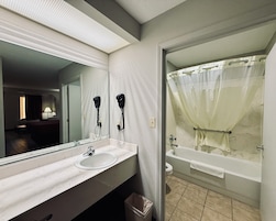 A bathroom with a sink, mirror, hair dryer, and bathtub.