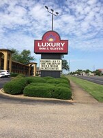 Señal de Luxury Inn & Suites destacando servicios como WiFi gratuito, desayuno, refrigerador pequeño y suites con jacuzzi.