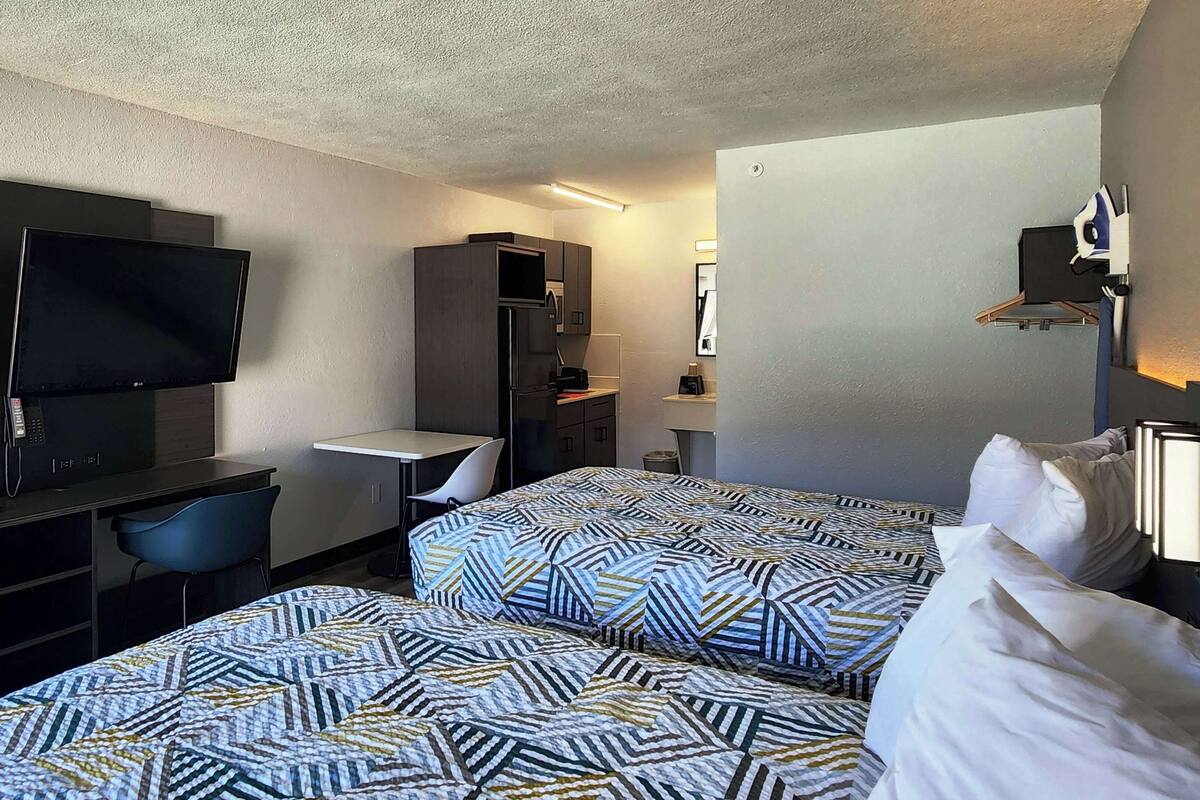 A hotel room with two beds, a desk, a TV, and a wardrobe.