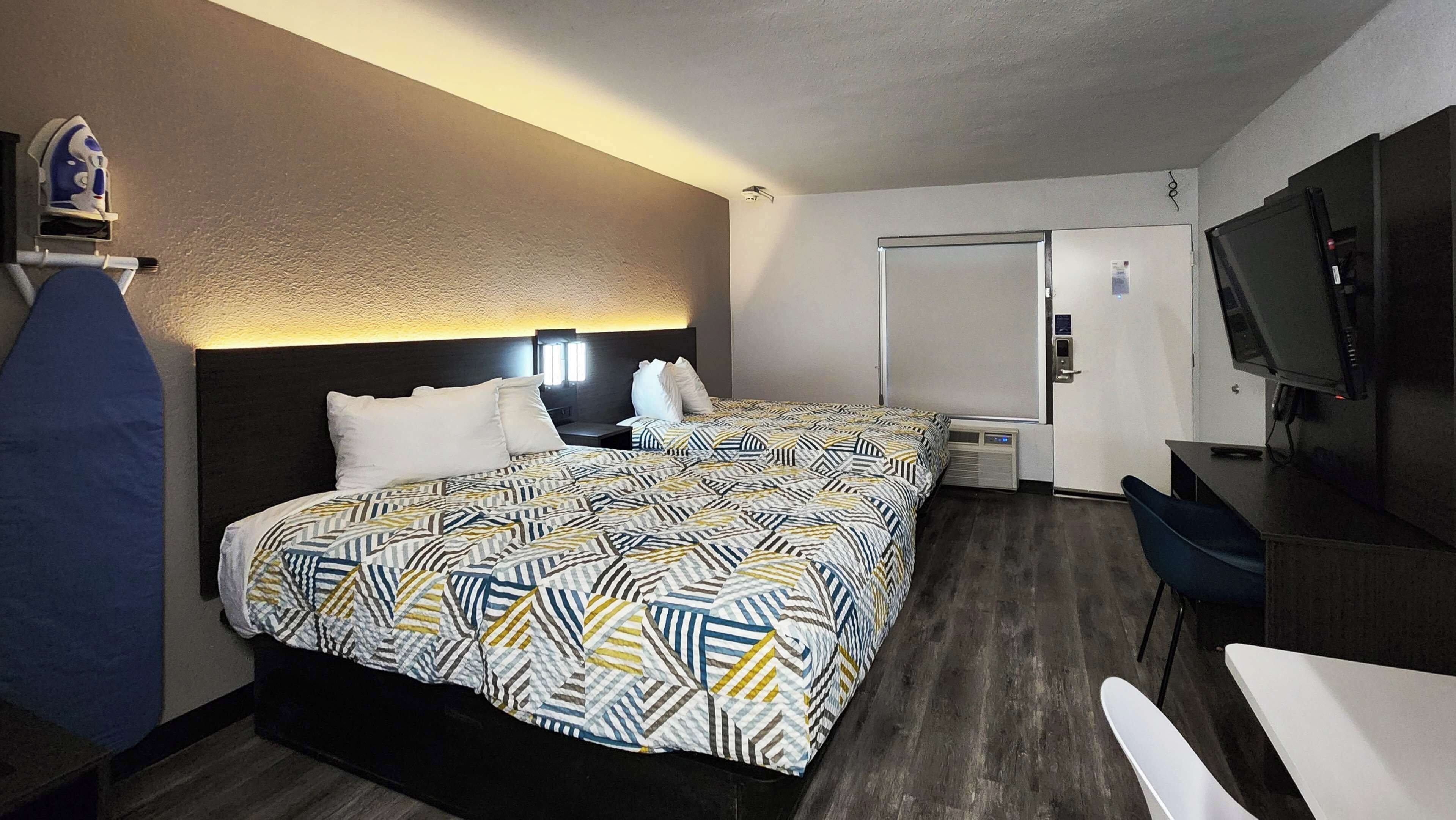 Una habitación de hotel con dos camas, un escritorio, un televisor y un mini bar.